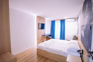 ein Schlafzimmer mit einem weißen Bett und blauen Vorhängen in der Unterkunft Hotel Bolero in Biograd na Moru