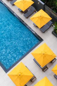 an overhead view of yellow umbrellas next to a swimming pool at Hotel IKON Phuket - SHA Extra Plus in Karon Beach