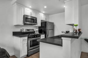 eine Küche mit weißen Schränken, einem Herd und einer Mikrowelle in der Unterkunft Fully Furnished 1 Bedroom Apartment with Full Bathroom in Koreatown Free Gated Parking Full Kitchen in Los Angeles
