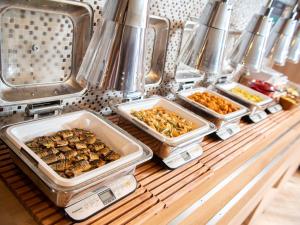 three trays of food sitting on a shelf in a kitchen at Super Hotel Sapporo Susukino in Sapporo