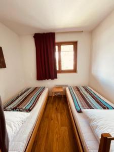 two beds in a small room with a window at Sunny Slopes Les Balcons de Recoin 6 pers in Chamrousse +6 photos