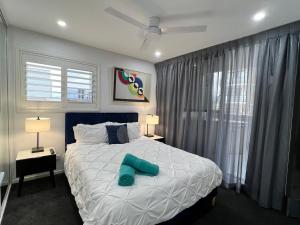 una camera da letto con un letto grande con testiera blu di 2BR Apt Gungahlin Square Luxe Super Central Wifi Wine Secure Parking a Canberra