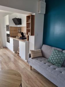 Una sala de estar con un sofá y una cocina. en Logement entier proche Nantes, en Geneston