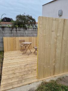 una terraza de madera con una mesa y una valla en Logement entier proche Nantes, en Geneston