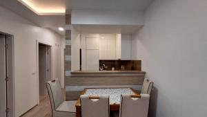 a dining room with a table and chairs and a kitchen at SMART LUX Apartment in Modriča