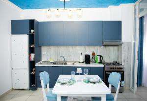 a kitchen with a white table and blue cabinets at Gjuhadol stay by Marina in Shkodër
