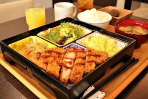 Una bandeja de comida con carne y verduras sobre una mesa. en Tabist TOKYO CITY VIEW HOTEL, en Tokio