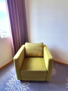 a yellow chair in a room with a window at Swiss-Belinn Manyar in Surabaya