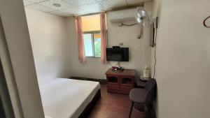 a small room with a bed and a television at Ron Gong Hotel in Chiayi City