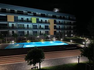 a building with a swimming pool in front of it at night at Római Ház Apartman in Siófok