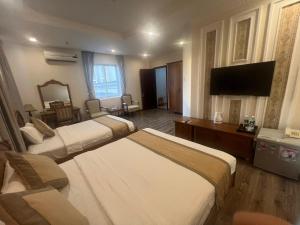 a hotel room with three beds and a flat screen tv at Madella Hotel in Can Tho