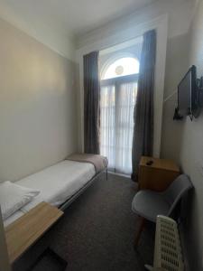 a small bedroom with a bed and a window at Lords Hotel in London