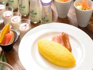 a plate with a hot dog and fruit on a table at Shin Furano Prince Hotel in Furano