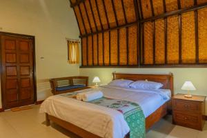 une chambre avec un grand lit avec des draps blancs dans l'établissement Green Orry Inn Tetebatu, à Tetebatu