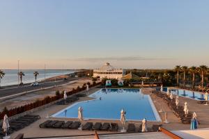 a large swimming pool next to a beach and the ocean at TAIGA Delta de l'Ebre in L'Ampolla