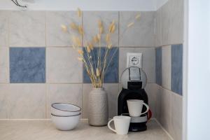a shelf with cups and a coffee maker and a vase with flowers at Eraora Lofts & Apartments Kefalonia in Lakithra +5 photos