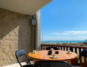 una mesa de madera en un balcón con vistas al océano en L'Abri Côtier, en Granville