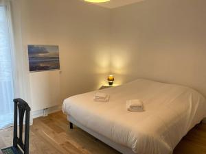 Un dormitorio con una gran cama blanca con dos toallas encima. en L'Abri Côtier, en Granville