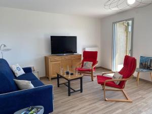sala de estar con 2 sillas rojas y TV en L'Abri Côtier, en Granville