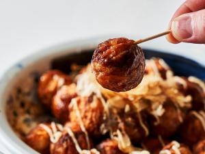a person holding a meatball on a stick in a bowl of food at Kobe Sannomiya Union Hotel in Kobe