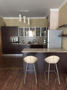 una cocina con dos taburetes blancos en un mostrador en Hatai Avenue 38 Apartment, en Baku