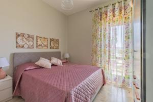 1 dormitorio con cama rosa y ventana en Terranova Home vista mare, en San Leone