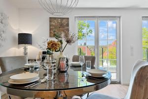 Un comedor con una mesa de cristal y sillas. en Penthouse Hafenkieker, en Putbus
