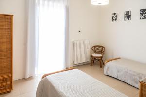 a bedroom with two beds and a chair and a window at Casetta Vacanze - Appartamento con 2 camere da letto in Frasso Telesino