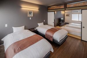 a hotel room with two beds and a television at Guest House HINATA - Japanese House with Sauna and Open-air Bath in Takayama