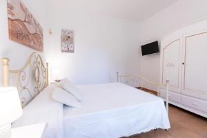 1 dormitorio blanco con 1 cama blanca y TV en Casa Giulia - vacanze a Olbia, en Olbia