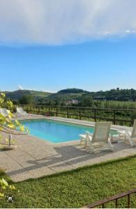 a swimming pool with two lawn chairs next to it at Cascina Longoria in Neive