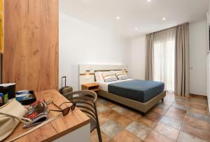 a bedroom with a bed and a table and a desk at Le Margherite in San Vito lo Capo