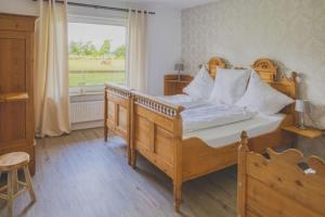 1 dormitorio con cama de madera y ventana en Landhaus Sonnenglück, en Tetenbüll