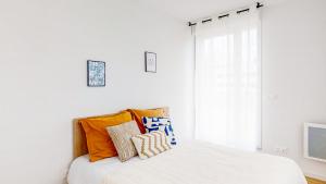 a white bedroom with a bed with orange pillows at Sweetly I-Art Gradignan - Bordeaux Sud in Gradignan