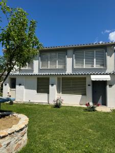 a white house with shuttered windows and a yard at VilaBakiaj in Tepelenë