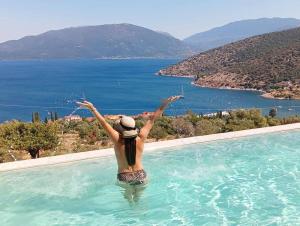 a woman in a swimming pool with her arms in the water at Augustela Villa SeaView Vacation Villa in Ayia Evfimia