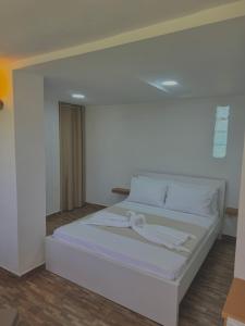 a white bed with a bow on it in a room at VilaBakiaj in Tepelenë