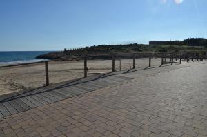a sidewalk next to a beach with a fence at Hotel Sant Jordi in Tarragona