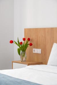 a vase with red flowers sitting on a night stand next to a bed at Mariinsky Boutique Hotel in Batumi