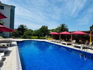a swimming pool with chairs and red umbrellas at Claude Monet beach hotel in Ureki