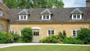 a brick house with a white door and windows at Wychwood Cottage in Bruern