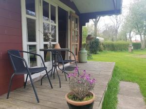 eine Veranda mit zwei Stühlen, einem Tisch und Blumen in der Unterkunft Rinkenæshus Hytte D in Gråsten