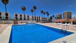 a large blue swimming pool with palm trees and buildings at Appartamento Altamar Las Americas in Playa de las Americas