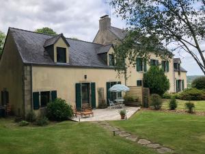 a large white house with a patio and umbrella at Le Relais - Maison avec grand jardin in Bannalec