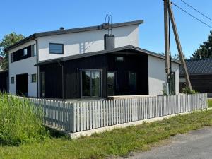 a white house with a fence in front of it at New Kuressaare Seaside Apartment in Kuressaare