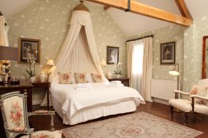 a bedroom with a white bed with a canopy at Cope Cottage in Bruern +13 photos