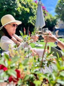 a woman sitting at a table with two glasses of wine at Hotel L'Escapade in Le Lavandou