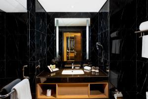 a black bathroom with a sink and a mirror at Swiss-Belhotel Airport Jakarta in Tangerang
