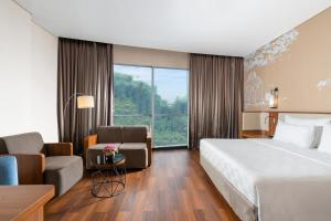 a hotel room with a bed and a couch and a chair at Swiss-Belhotel Airport Jakarta in Tangerang
