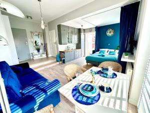Una sala de estar con un sofá azul y una mesa. en Sunset Apartments Kropla Baltyku, en Darłówko